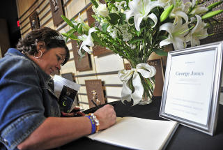 KONDOLANSEPROTOKOLL: Kathy Magaleski fra New Jersey skriver i kondolanseprotokollen som er lagt ut i Country Music Hall of Fame i Nashville, Tennessee. Foto: AP / NTB Scanpix