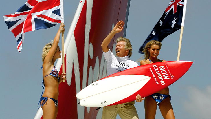 LUFTIG: Richard Branson, eieren av flyselskapet Virgin Atlantic, liker luftig p�kledning, s�rlig p� damene, n�r han lanserer noe nytt, og gjerne et nummer i lufta. Han har for lengst innr�mmet at han er medlem av 10 000 meters klubben. N� introduserer han fl�rt i lufta. Her st�r han med to modeller p� vingen av et fly i Sidney i anledning en ny flyrute. Foto: DAVID GRAY / REUTERS / NTB SCANPIX