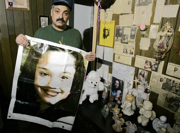 MINNESTED: Her er Felix DeJesus med en plakat av sin savnede datter Gina. Bildet ble tatt i mars 2004. Foto: AP Photo/Tony Dejak, File/NTBScanpix