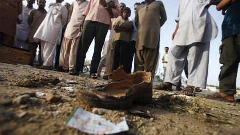 BLODIG KAMPANJE:  Skuelystne ser p� en �delagt sko som ligger igjen uten eier p� bakken etter en bombeeksplosjon tirsdag denne uka. Her var bomben rettet mot kampanjekontoret til partiet Muttahida Qaumi Movement (MQM) i Karachi. Minst fem ble drept, 15 skadd. �rets valgkampanje er den blodigste i Pakistans historie. Foto: Athar Hussain/Reuters/Scanpix