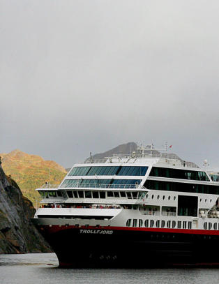 Fjorden ligger rolig med dypbl�tt vann, fossefall og gr�nne bredder