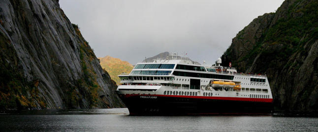 Fjorden ligger rolig med dypbl�tt vann, fossefall og gr�nne bredder