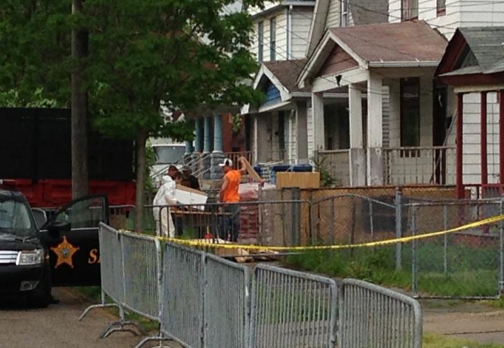 STOR AKTIVITET: En �stedsgransker i hvit drakt b�rer ei kasse inn i huset til Ariel Castro i 2207 Seymour Avenue i Cleveland. Arbeidere utenfor gj�r klar sponplater som trolig skal brukes til � barrikadere huset. Foto: VEGARD KRISTIANSEN KVAALE / DAGBLADET