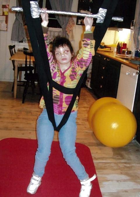 TRENING: Ane sitter i rullestol og har et st�stativ som gj�r at hun f�r strekt ut og styrket bena sine. Hun kommuniserer med emosjoner og mimikk.  Foto: privat