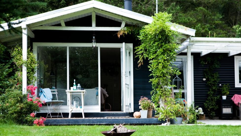 LITEN OG SJARMERENDE: Den vesle hytta med anneks rommer mer enn man tror. Terrassed�ren fra stuen f�rer direkte ut til den overdekte terrassen, der det alltid er le. Selv om vinteren kan man sitte ute og drikke en kopp kaffe. Stilen er enkel og lys med gode, funksjonelle designm�bler, og gamle, robuste m�bler. FOTO: Tia Borgsmidt