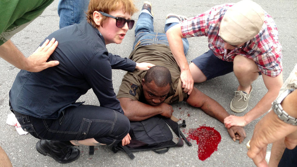  SKUTT UNDER PARADE:  Bildet viser en mann som  f�r hjelp av forbipasserende, etter � ha blitt skutt under paraden. S� langt er det ikke meldt om d�dsfall. Foto: AP