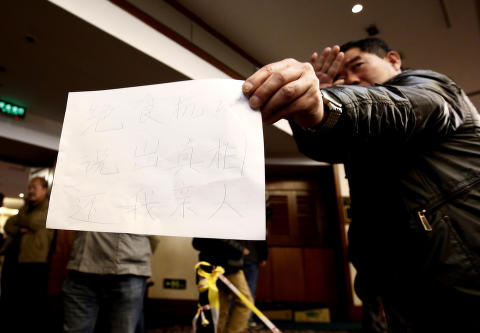 <b>SULTESTREIK:</b> En pårørende ved et hotell som fungere som pårørendesenter i Beijing holder fram en lapp med teksten: "Sultestreik. Gi oss sannheten. Gi oss våre familier tilbake".