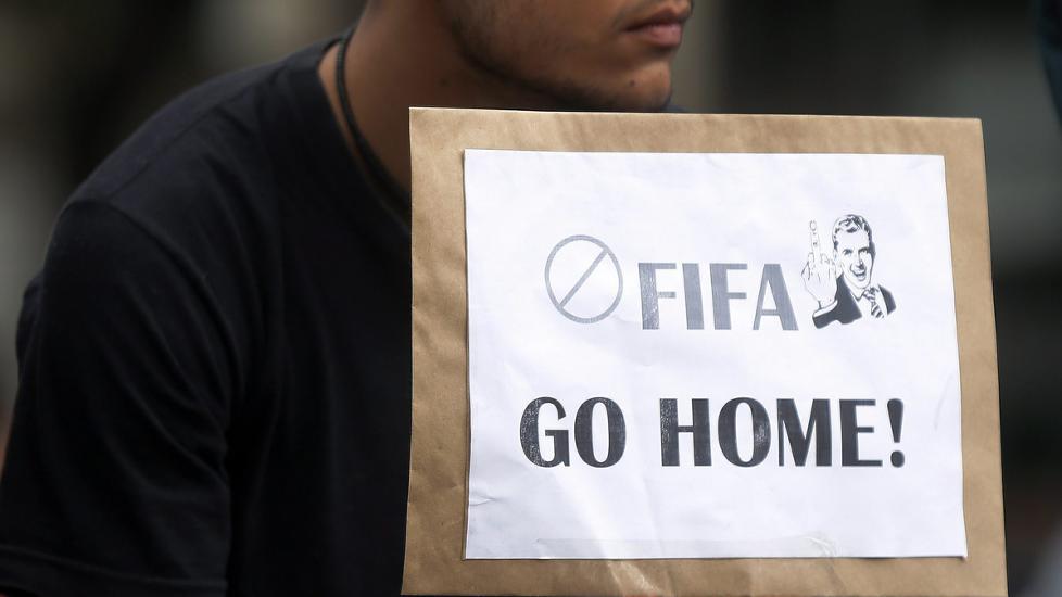 <b>KONTRASTER:</b> I Sao Paulo er det folkefest på arenaen, mens det samtidig er demonstrasjoner over hele landet. Her gjør en demonstrant det helt klart hva han synes om FIFA og Sepp Blatter.
