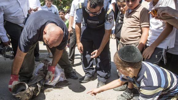 Israelske bombeeksperter plukker opp restene av en rakett som skal ha vært skutt opp av palestinske militante i Gaza, foran skuelystne barn. Raketten skal ikke ha ført til skader av betydning, der den landet utenfor Netivot i Israel. 