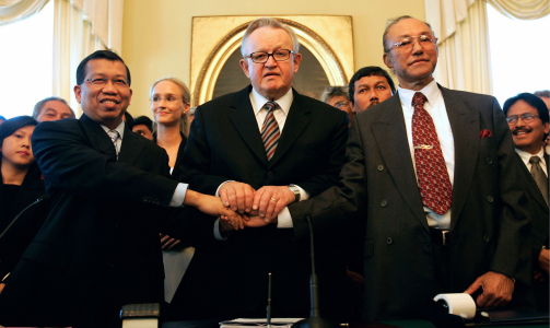 FREDSAVTALE: Indonesias justisminister Hamid Awaluddin (t.v.) h�ndhilser p� p� lederen for Fritt Aceh-bevegelsen Chairman Malik Mahmood (t.h.) sammen med Ahtisaari, 15. august 2005. Fredsavtalen avsluttet flere ti�rs konflikt i Aceh-provinsen i Indonesia.  Foto: REUTERS/Ruben Sprich