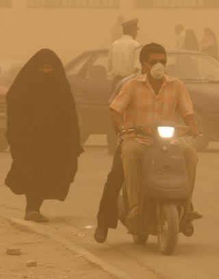 SANDSTORM: Innbyggerne i Kerbala dekker seg til som mest de kan for � komme seg fram i st�vet som omringer byen. Foto: Mushtaq Muhammed, Reuters
