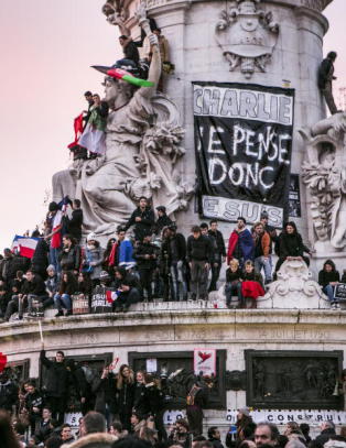 Latterliggjør folkesamlingen i Paris etter terrorangrepet, med 11. september og de drepte tegnerne i bakgrunnen
