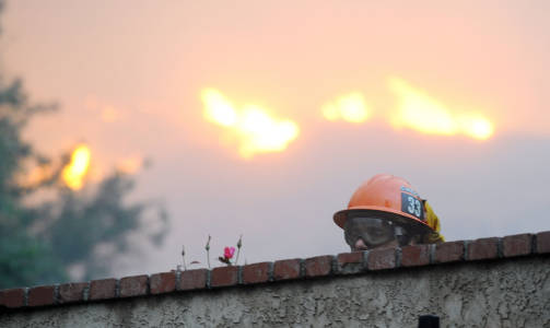 BRANNMANN: En brannmann titter over en mur i  Montecito. Foto: AFP PHOTO/Robyn BECK
