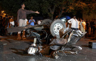 MINST 80 DREPT: Forbipasserende ser p� vraket av en bil, etter at terrorister slo til i en koordinert aksjon mot flere m�l i Mumbai. Foto: REUTERS/Stringer/SCANPIX