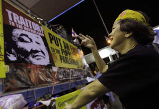 VIL IKKE GI SEG: En av de omkring 10 000 demonstranter som okkuperer hovedflyplassen i Bangkok, danser foran en plakat av landets tidligere statsminister Thaksin Shinawatra. Okkupantene krever at landets n�v�rende statsminister, Somchai Wongsawat, g�r av umiddelbart. Foto: AP PHOTO/SCANPIX