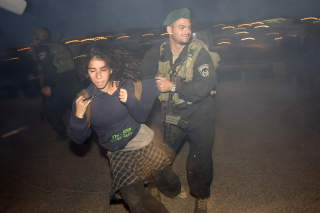 P�GRIPELSE: En israelsk grensepolitimann p�griper en ung settlerkvinne utenfor det okkuperte huset i Hebron. Unge settlerjenter i Hebron er kjent for � g� p� jakt etter palestinere. Steinkasting og spyttinger er langt fra uvanlig, noe Dagbladet.nos journalist har observert ved selvsyn flere ganger. Foto: AFP/Scanpix