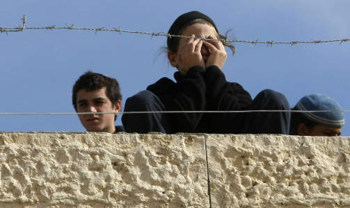 BER OM HJELP: En ung settler sitter p� taket av det okkuperte huset i Hebron som, rundt klokka 14 norsk tid, n� fors�kes evakuert av den israelske h�ren. Et stort antall ultranasjonalistiske settlere fra hele Vestbredden har barrikadert seg i huset, klare til � kjempe mot sin egen stats soldater. Foto: AFP/Scanpix