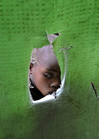 LEVER I FRYKT: En ung, kongolesisk gutt titter ut av teltet han bor i i en flyktningeleir n�r grensa til Rwanda. Foto: AFP PHOTO/ Tony KARUMBA/Scanpix