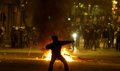 KASTER STEIN: En ungdom kaster stein mot politiet i Aten sentrum i kveld. Foto: AP Photo/Petros Karadjias/SCANPIX