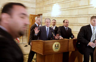 TOK DET ROLIG: President George W. Bush l�ftet hendene avvergende, etter at skoene var falt. Det gjorde ikke sikkerhetsfolkene p� arbeid. Mannen ble drarr skrikende ut av salen. Evan Vucci/AP