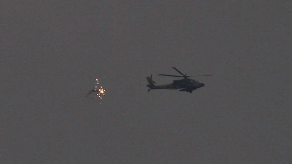 PATRULJERER I M�RKET: Et helikopter slipper ut lyselementer over den israelsk-palestinske grensen. Omr�dene herjes av massive rakettangrep. Foto:DAN BALILTY/AP/SCANPIX