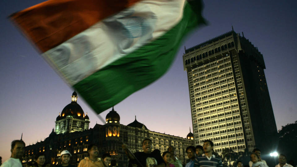 NASJONAL STOLTHET: En mann vifter med det indiske flagget foran Taj Mahal-hotellet, et av m�lene for Mumbai-terroristene. Forholdet mellom India og Pakistan forverres stadig. Foto: Rajanish Kakade/AP/Scanpix