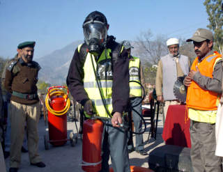 DEMONSTRERER UTSTYRET: Et medlem av det pakistanske forsvaret demonstrerer milit�rt utstyr foran nygjerrige tilskurere i Muzaffarabad i Kashmir. Det mobiliseres n� p� begge sider av grensen. Foto: Sajjad Qayyum/AFP/Scanpix