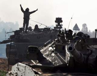 FLYTTES TIL GRENSA: En israelsk stridsvognskytter st�r p� toppen av sin Merkava-stridsvogn og viser V-tegnet, i det israelske styrker
er p� vei til grensa mot Gaza.
Foto: EPA/JIM HOLLANDER/SCANPIX