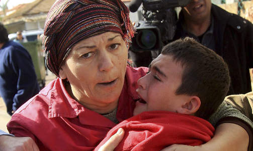 PR�VER � TR�STE: En kvinne tr�ster en livredd ung gutt etter et palestinsk rakettangrep p� byen Ashkelon. Foto: Edi Israel/AP/Scanpix
