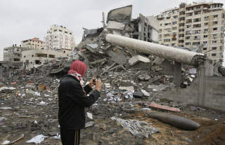 STORE �DELEGGELSER: En palestinsk mann tar et bilde av en israelsk bombe som ikke gikk av, like ved justisdepartementet som ble truffet tidligere i dag. FOTO: AFP PHOTO/MAHMUD HAMS/SCANPIX