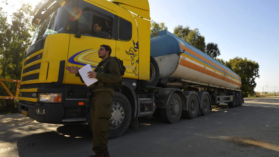 ENDELIG FORSYNINGER: En isralesk soldater sjekker en tankbil som har levert drivstoff til Gazastripen. I tre timer stanset israelerne angrepene i dag for � slippe inn n�dhjelp. Men klokka 16 var kampene i gang igjen. Foto: Amir Cohen/Scanpix/Israel