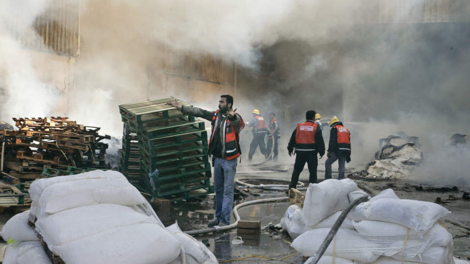 I BRANN: FN-arbeidere og palestinske brannfolk arbeider med � slukke brannen i UNRWA-hovedkvarteret, og redde sekker med mat som ble oppbevart i en lagerbygning. Foto: HATEM MOUSSA/AP/SCANPIX