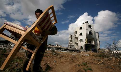 TAR MED SEG DET SOM ER IGJEN: En palestiner tar med seg en stol som fortsatt er intakt etter bombingene i Gaza i dag. Foto:  EPA/MOHAMMED SABER/SCANPIX