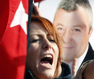 F�R ST�TTE: En supporter roper ut sin st�tte til de mange som er blitt fengslet i saken, like ved et bilde av en av dem; journalist Tuncay Ozkan. FOTO: REUTERS/FATIH SARIBAS/SCANPIX