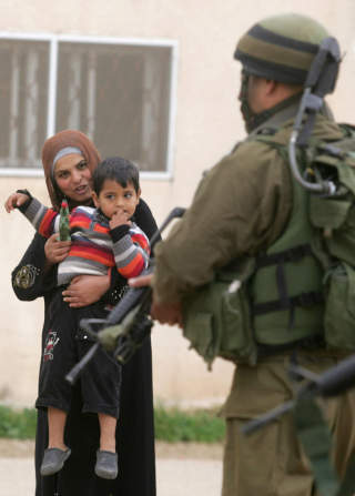 HJELPER TIL I DEN ISRAELSKE H�R: Flere bibeltro kristne drar til Israel for � jobbe blant annet som ingeni�rer og logistikkmedhjelpere i Det israelske forsvaret.  Bildet viser en palestinsk mor og hennes s�nn sammen med en israelsk soldat p�  Jenin p� Vestbredden.
AFP PHOTO / SAIF DAHLAH