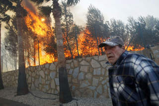 EVAKUERTE: En mann flykter fra flammene som herjet La Nucia i Spania i helgen. Foto: SCANPIX/AFP PHOTO/MANUEL LORENZO