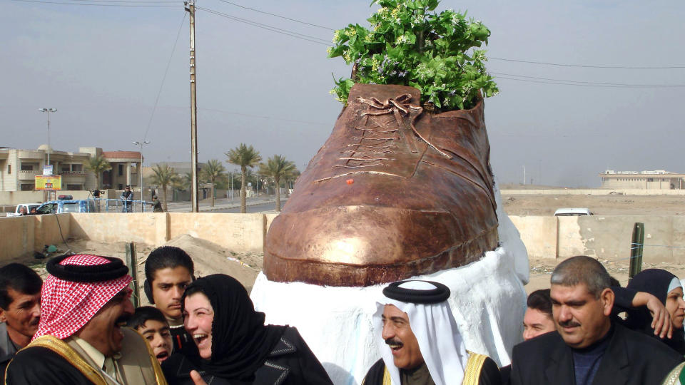 UD�DELIGGJORT: Latter og glede n�r en bronseutgave av skoen slynget mot George Bush blir avduket i monumentsform i byen Tikrit utenfor Bagdad. Foto: AFP PHOTO/MAHMUD SALEH/Scanpix