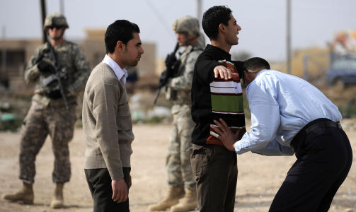 RANSAKES: To menn er p� vei til � avgi sine stemmer i byen Khanaquin. Amerikanske soldater holder vakt i bakgrunnen. Foto: Filippo Monteforte/AFP/Scanpix
