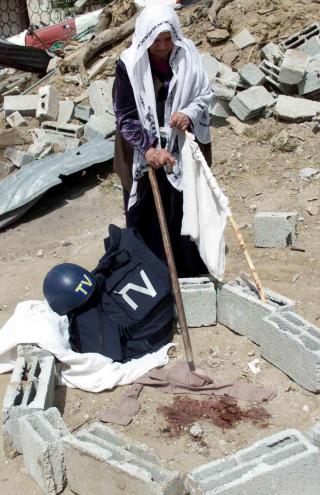 DREPT: En palestinsk kvinne viser stedet der Miller d�de 2. mai 20003. Hjelmen og vesten ligger igjen. Det samme gj�r et hvittt flagg. Foto: AFP/Mohammed ABED/SCANPIX