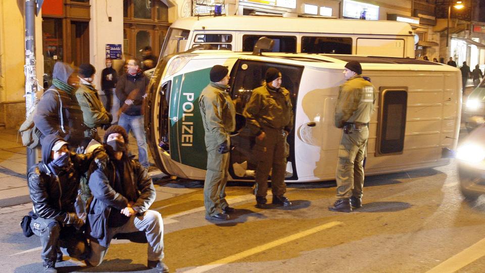 BARKET SAMMEN: Det gikk hardt for seg under demonstrasjonen i helgen. Her poserer et par demonstranter foran en veltet politibil. Foto: EPA/JAN WOITAS/SCANPIX