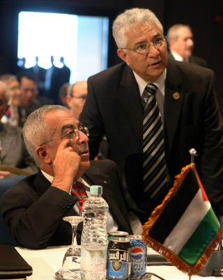 P� PLASS, MEN UTEN ST�TTE: Palestinernes statsminister Salam Fayyad (sittende) snakker med sin utenriksminister Riyad al-Maliki like f�r giverlandskonferansen startet i formiddag. De to representerer Fatah, som har liten st�tte blant den palestinske befolkningen. Den folkelige st�tten har Hamas, men de f�r ikke stille p� dagens m�te. Foto: Cris Bouroncle/Afp/Scanpix