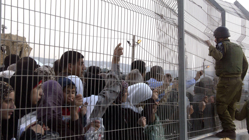 ENORME HINDRINGER: En israelsk soldat pr�ver � f� oversikten over palestinerne som st�r i k� ved det nye Hawara-sjekkpunktet utenfor byen Nablus, nord p� Vestbredden. Nesten ingen palestinere i Nablus f�r kj�re bilen sin ut av den palestinske byen, for � komme til andre byer lenger s�r p� Vestbredden. Det f�r imidlertid de israelske bosetterne som bor like utenfor Nablus. Bosetterne har egne veier som g�r over hele Vestbredden. Foto: Jaafar Ashtiyeh/Afp/Scanpix