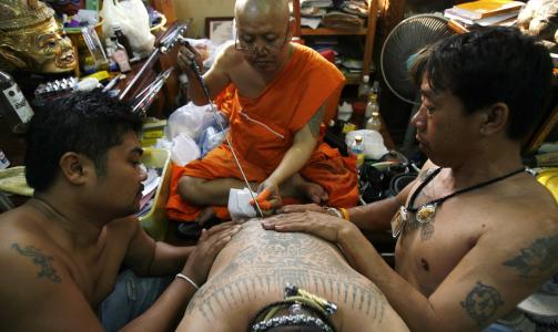 SKAL BESKYTTE MOT UFLAKS: Deltakerne blir tatovert av munker. Foto: REUTERS/Chaiwat Subprasom/Scanpix