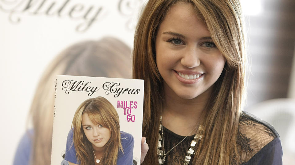 SELVBIOGRAFI: 16 �r er tydeligvis ikke for ungt til � utgi en selvbiografi. Her poserer Miley Cyrus med boka Miles To Go. Foto: Scanpix