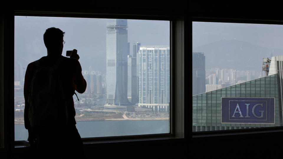VERDENS ST�RSTE VAKLER: En mann tar bilde av AIGs kontorer i Hongkong. Verdens st�rste forsikringsgigant g�r med store tap hver dag og holder seg flyetnde p� skattebetalernes penger. Foto: REUTERS/Bobby Yip/SCANPIX