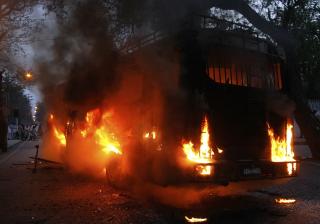 FLAMMER: En buss st�r i brann, etter � ha blitt p�tent av demonstranter i Lahore. Sentrum av byen ser ut som en krigssone, if�lge nyhetsbyr�ene. Foto: Mohsin Raza/REUTERS/Scanpix