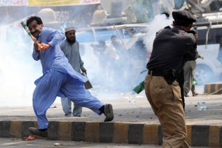 KAOS: En politisk aktivist fors�ker � l�pe fra t�regassen til en politimann i Lahore. Foto: Asif Hassan/AFP/Scanpix