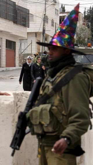 UBLU KLESVALG:Haaretz rapporterer om flere provoserende tr�yer i sirkulasjon blant israelske soldater. Denne soldaten har imidlertid valgt � if�re seg en trollmannhatt, noe palestinske forbipasserende virker noe skeptiske til. Foto: Jim Hollander/EPA/Scanpix