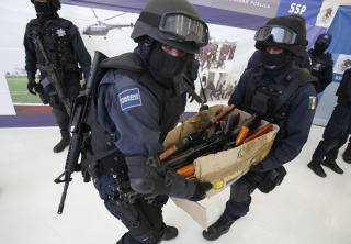 V�PNA TIL TENNENE: Politet b�rer v�penbeslag etter en razzia ved Mexico City i februar. USA tar p� seg ansvaret for at gjengene er ekstremt godt bev�pna. Foto: SCANPIX/AP Photo/Dario Lopez-Mills