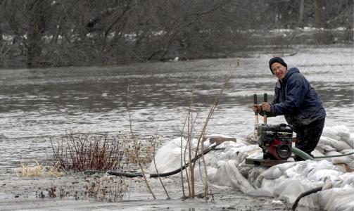 FLOM: En av Fargos innbyggere pr�ver � lede vannet bort fra sitt hjem.  EPA/CRAIG LASSIG